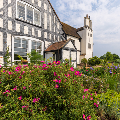 The black and white timber-framed Boscobel House with pink flowers in the garden in the foreground.