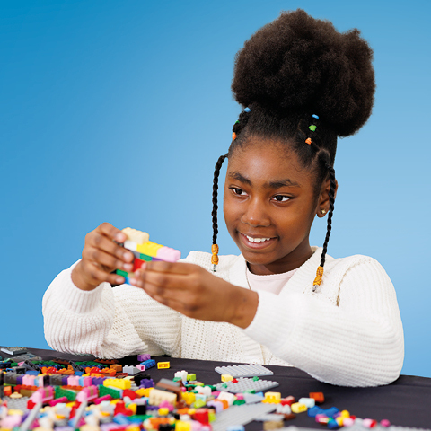 A girl sits playing with Lego bricks