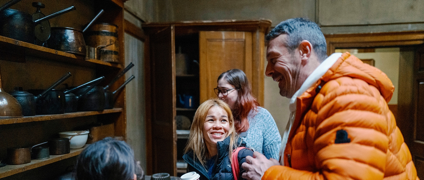 A man and a woman smile while talking to an English Heritage volunteer guide.