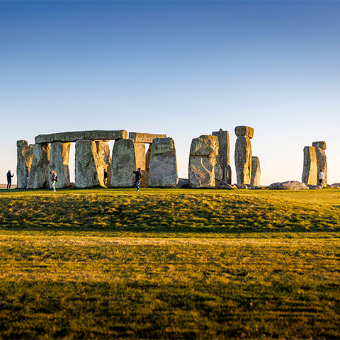 The large stone circle of Stonehenge seen across some grass