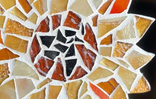 A close-up image of a colourful flower shaped mosaic tile.